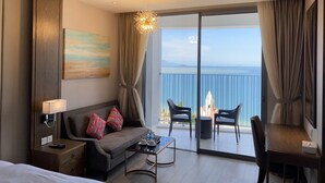 Ein Hotelzimmer mit Balkon, einer Couch, einem Couchtisch und Meerblick.