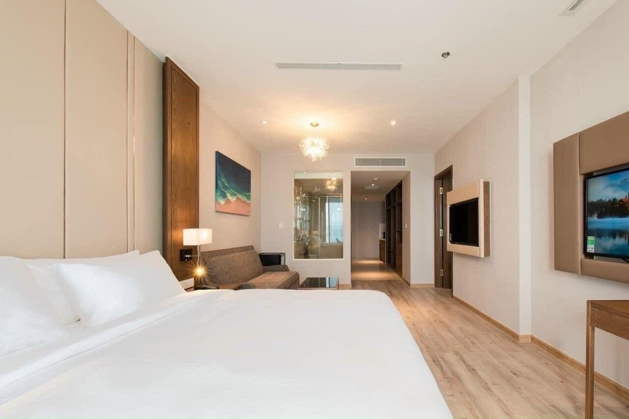 Une chambre d’hôtel avec un grand lit, un bureau, une chaise, une télévision et un tableau au mur.