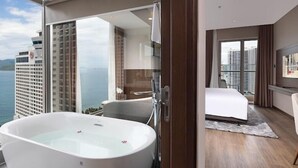 Ein modernes Hotelzimmer mit einer großen Badewanne, einem Bett und Blick auf die Stadt.
