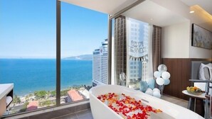 Ein modernes Badezimmer mit einer großen Badewanne, gefüllt mit Rosenblüten, Meerblick und Geburtstagspflanzen.