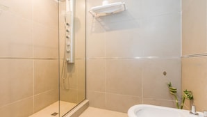 Une salle de bain moderne avec une douche à parois de verre, un lavabo blanc et un porte-serviettes.