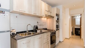 Une cuisine moderne avec des meubles en bois clair, un plan de travail en granit, des appareils électroménagers en acier inoxydable et un four apparent.