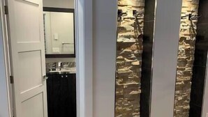 A hallway with a wooden floor, a white door, and two vertical stone wall panels. - Fully Remodeled Luxury 1BR | Gondola • A/C • Steam Shower (Telluride)