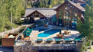 A resort with a pool, outdoor seating, and a large wooden building. - 2 BR Condominium - Luxury ski-in/ski-out (rare find) (Telluride)
