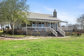 A single-story house with a porch, a chimney, and a fenced yard. - Cozy Ranch Home minutes from Brenham, Bellville, Round Top! (Brenham)
