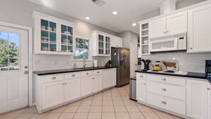 Una cocina moderna con armarios blancos, un refrigerador de acero inoxidable y una encimera negra.