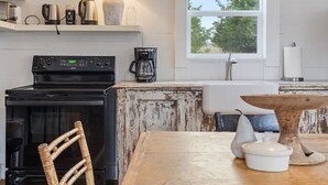 A rustic kitchen with a wooden table, chairs, and a hanging light fixture. - Rustic Charm in our Quaint Round Top Farmhouse! (Round Top)