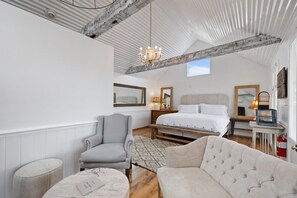 A bedroom with a bed, a chair, a table, and a chandelier. - Lakefront Charm: Your Perfect Getaway in Round Top (Fayette County)