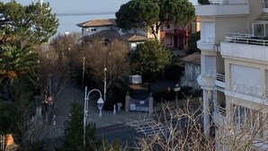 Zona residenziale con vista mare aperta, una strada alberata e un edificio con balconi.