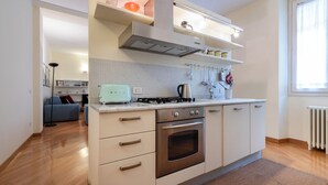 A modern kitchen with a built-in oven, a gas stove, and a toaster. There is a window providing natural light and a radiator on the wall.