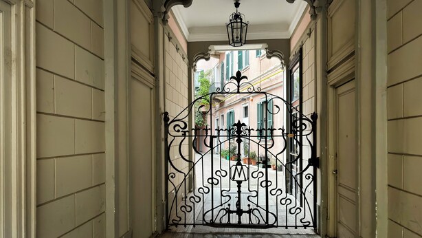 A narrow hallway with a wrought iron gate leading to a street.