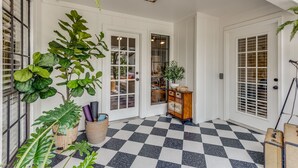 Un sòl a quadradets, portes blanques i plantes en testos en un passadís.