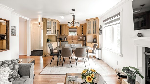 A modern kitchen with wooden cabinets, a dining area with a table and chairs, and a living room with a sofa and a coffee table. - Cozy 3 bedroom  condo in Magog with a semi private loft.Great location. (Magog)