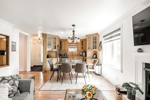 Una cocina moderna con armarios de madera, un comedor con mesa y sillas, y una sala de estar con sofá y mesa de centro.