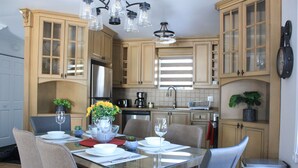 A modern kitchen with wooden cabinets, a stainless steel refrigerator, and a dining table set for four. - Cozy 3 bedroom  condo in Magog with a semi private loft.Great location. (Magog)