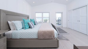 Quarto moderno com uma cama grande, vista da cidade e um guarda-roupa de portas deslizantes.