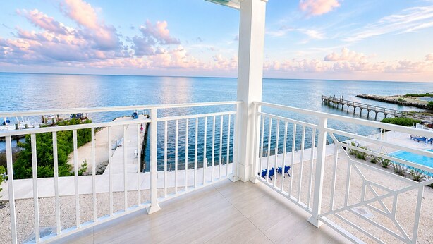Uma varanda com vista para o mar, uma piscina e um cais.
