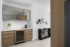 A modern kitchen with a white countertop, wooden cabinets, a large mirror, and decorative wall mirrors.