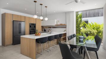 A modern kitchen with a central island, bar stools, and a dining table with chairs.