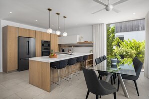 Una cocina moderna con una isla central, taburetes de bar y una mesa de comedor con sillas.
