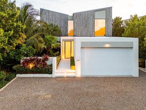 Une maison moderne avec un garage, un jardin bien entretenu et un chemin dégagé menant à l’entrée.