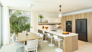 Une cuisine moderne avec un îlot central, des tabourets de bar blancs et un grand réfrigérateur.