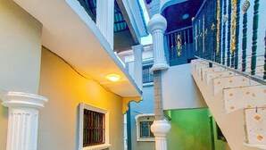 Un intérieur à plusieurs niveaux, doté d’un sol carrelé, de colonnes blanches, d’un escalier et d’un balcon agrémenté d’une balustrade.