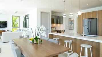 Uma cozinha moderna com ilha central, banquetas e uma mesa de jantar com cadeiras.