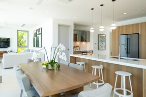Une cuisine moderne dotée d’un îlot central, de tabourets de bar et d’une table à manger avec des chaises.