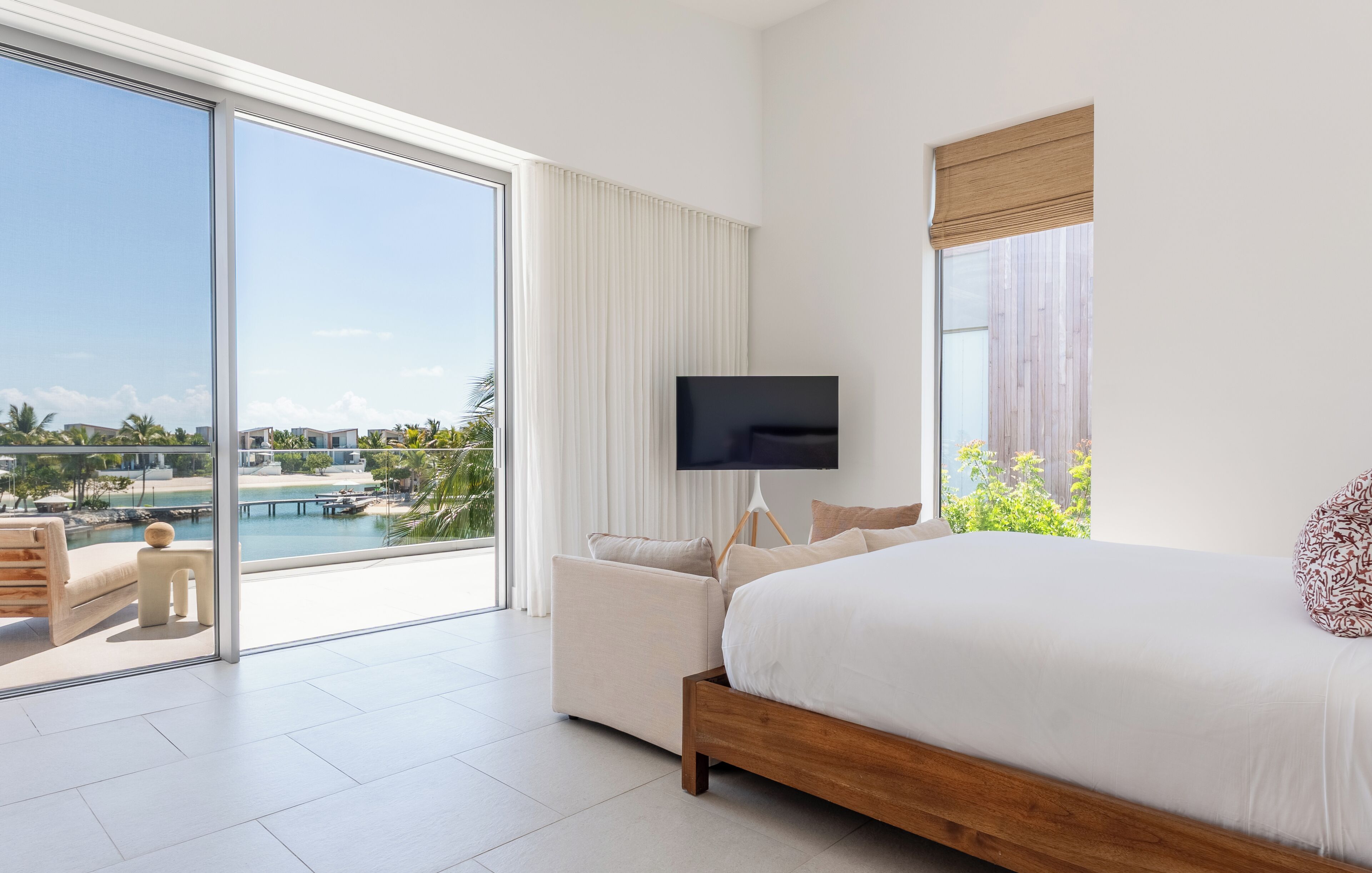 Ein Hotelzimmer mit einem großen Bett, einem Fernseher und Blick auf einen Pool und Palmen.