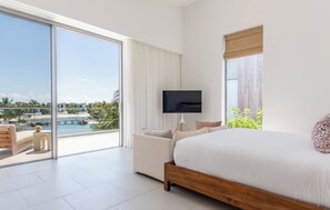 Ein Hotelzimmer mit einem großen Bett, einem Fernseher und Blick auf einen Pool und Palmen.