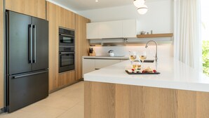 Una cocina moderna con una isla integrada, electrodomésticos de acero inoxidable y una zona para desayunos con copas de vino y fruta.