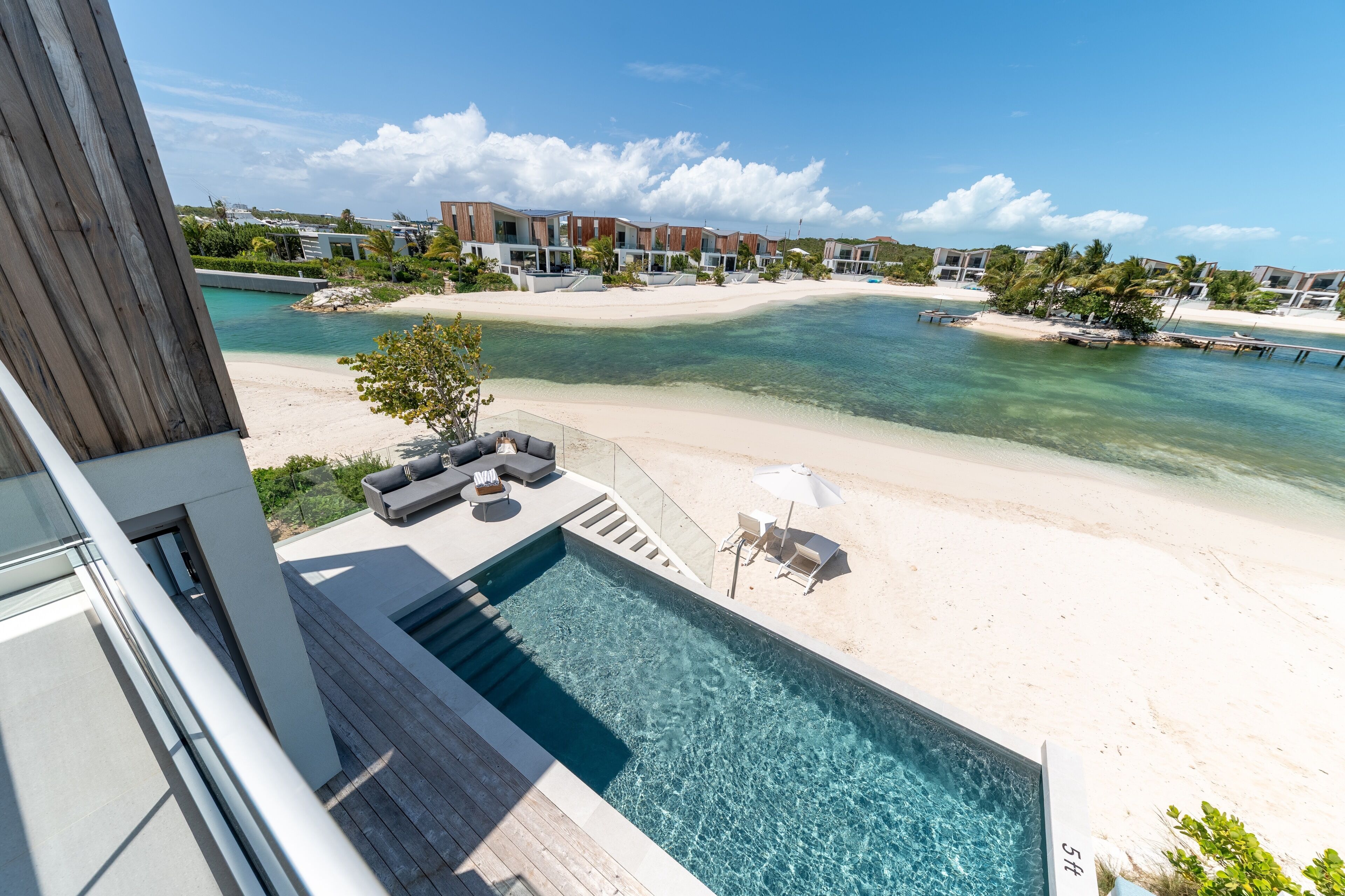 Un resort moderno con piscina, playa y vista al océano.