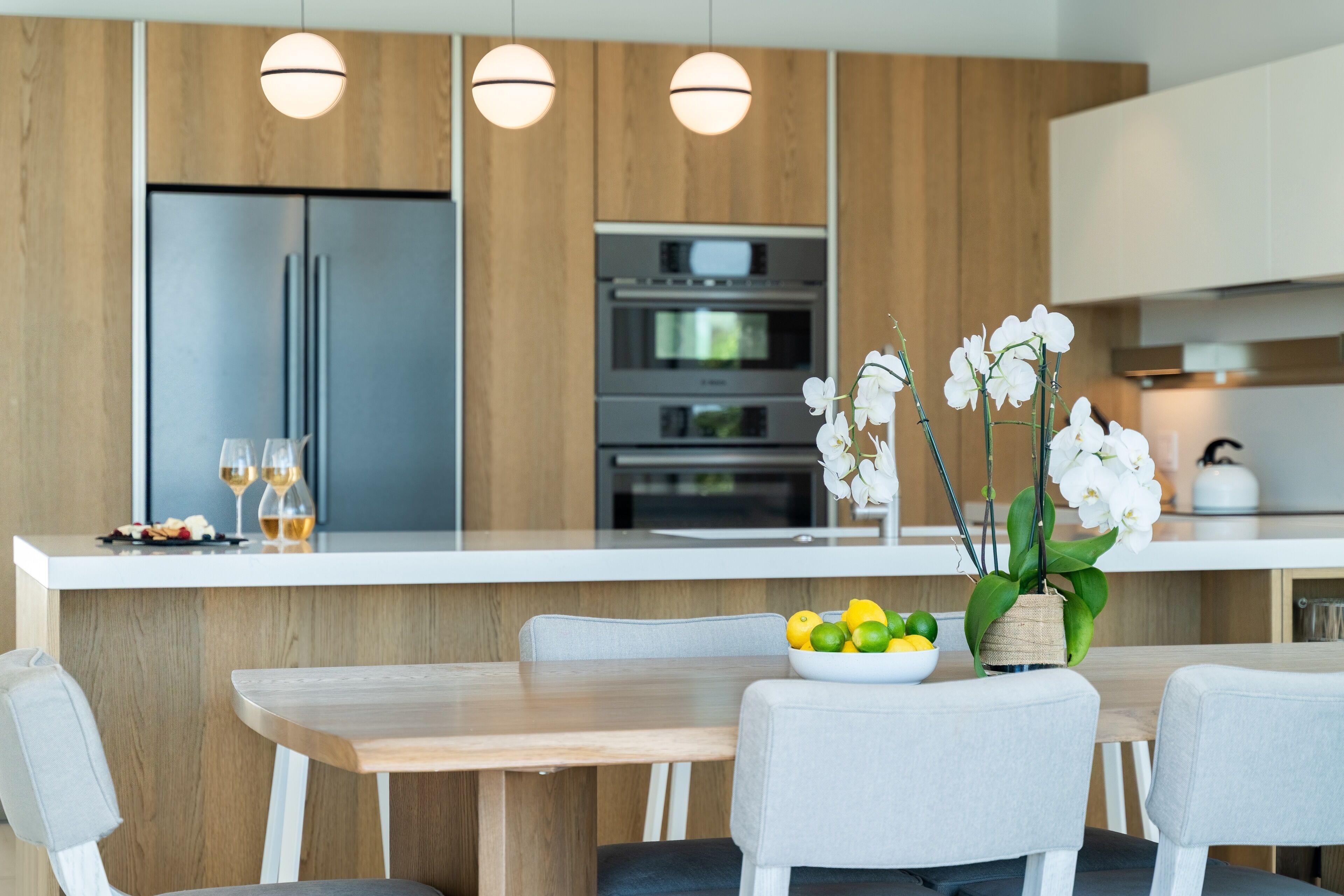 Una cocina moderna con una isla central, electrodomésticos integrados y un comedor con sillas y mesa.