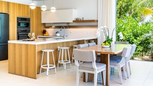 Cocina moderna con una isla central, taburetes de bar y una mesa de comedor con sillas.