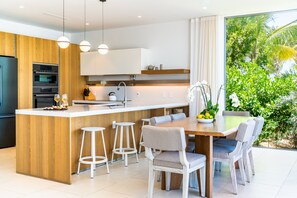 Een moderne keuken met een centraal eiland, barstoelen en een eettafel met stoelen.