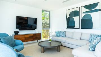 A modern living room with a grey sofa, blue armchairs, a coffee table, and abstract wall art.