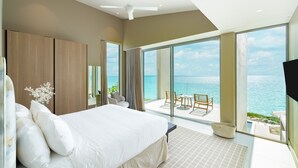 A modern bedroom with a large bed, a ceiling fan, and a balcony with a view of the sea. - Ocean Estate Reef 5 Bedroom Including Guesthouse OE10 (Providenciales)