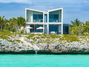 Un moderno edificio de dos pisos con amplios ventanales, una piscina y zona de estar exterior.