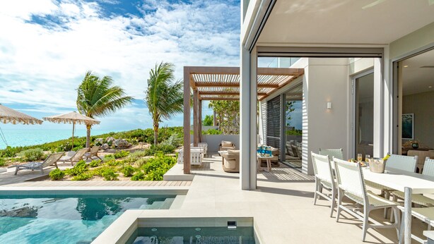A modern outdoor pool area with lounge chairs, a pergola, and a dining table with chairs. - Ocean Estate Reef 5 Bedroom Including Guesthouse OE10 (Providenciales)