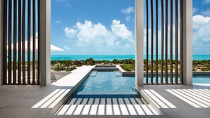 A modern infinity pool with a clear view of the ocean and a tropical landscape. - Ocean Estate Banks 5 Bedroom OE14 (Providenciales)