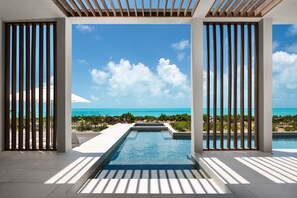 Ein moderner Infinity-Pool mit freiem Blick auf den Ozean und eine tropische Landschaft.
