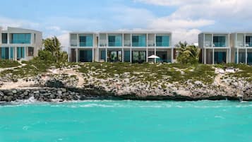 A beachfront hotel with multiple-story buildings, balconies, and a clear view of the turquoise ocean.