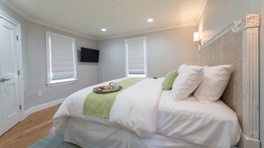 Un dormitorio con cama, una bandeja de desayuno, televisor y ventana.