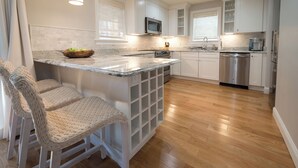 Una cocina moderna con armarios blancos, encimera de granito y lavavajillas de acero inoxidable.