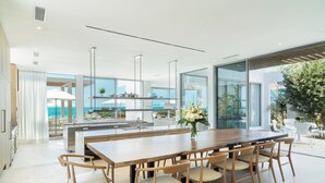 Una cocina moderna con una isla grande, armarios blancos y vistas al océano.