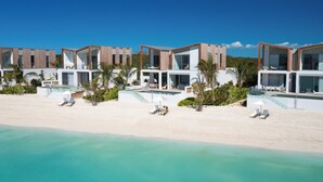 Un resort frente a la playa con arquitectura moderna, piscina y servicios junto a la orilla.