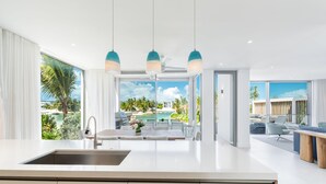 Cocina moderna con una isla grande, pileta integrada y vista a una piscina y zona de estar al aire libre.