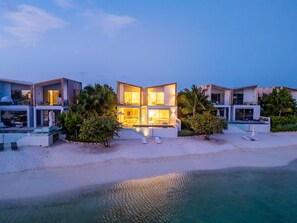 Une propriété située en bord de mer, comprenant plusieurs villas modernes, une piscine et une plage.