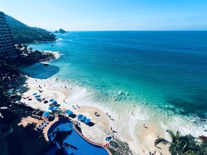 Un complexe hôtelier de bord de mer doté d’une piscine, de chaises longues et de parasols.